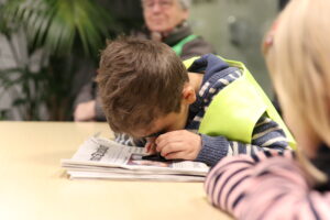 Kinder nehmen die Zeitung unter die Lupe - Foto Ein Kind untersucht mit einer Lupe eine Ausgabe des Mindener Tageblatts